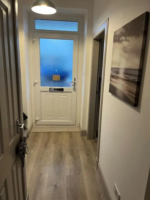 a hallway with a white door and a window at Willow's Cottage in Auldearn