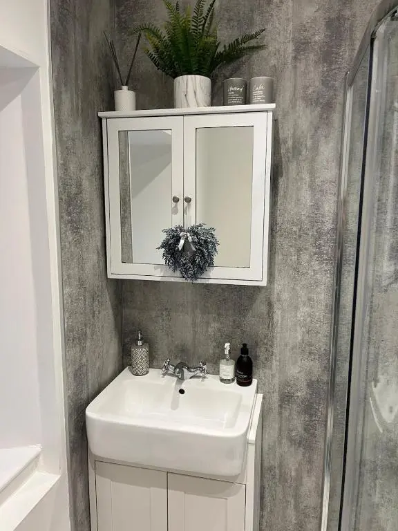 a bathroom with a white sink and a cabinet at Willow's Cottage in Auldearn
