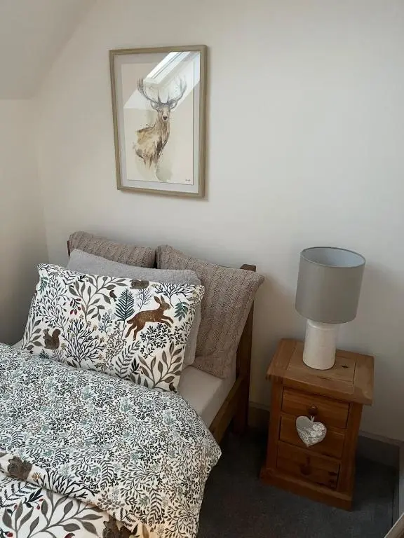 a bedroom with a bed and a table with a lamp at Willow's Cottage in Auldearn