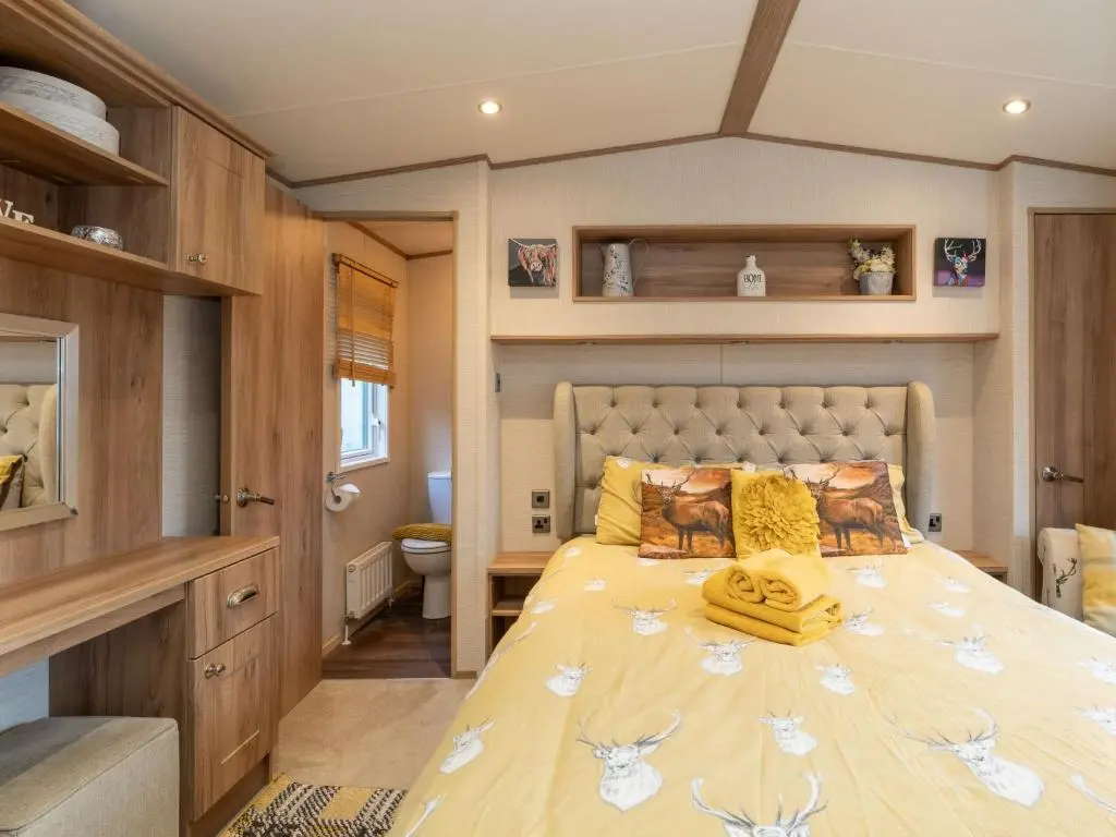 a bedroom with a large bed with yellow pillows at Chalet Cairn View by Interhome in Aviemore