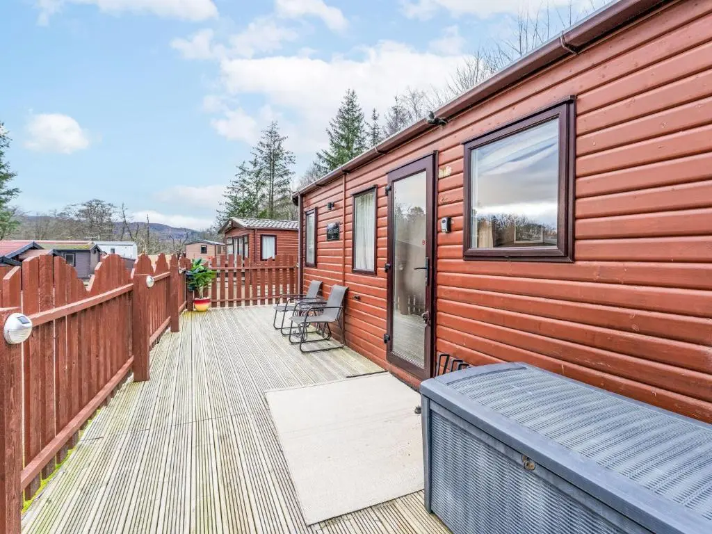a wooden cabin with a deck with benches on it at Chalet Cairn View by Interhome in Aviemore