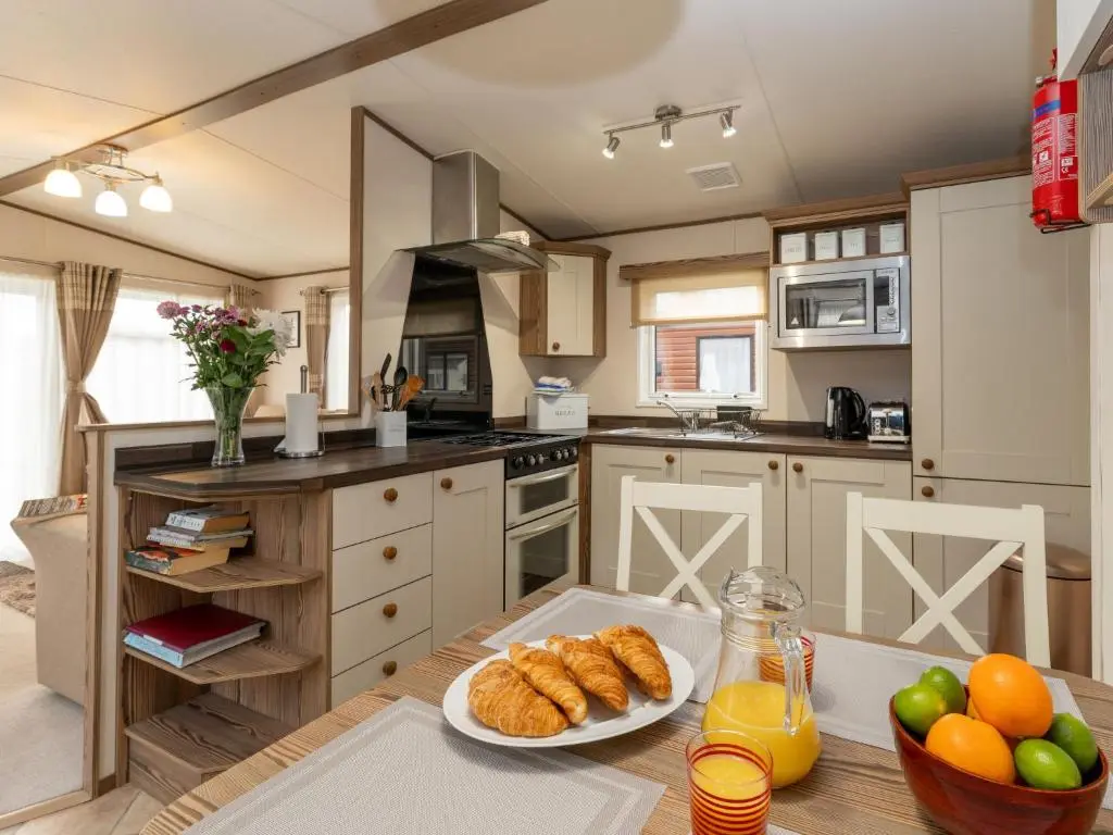 a kitchen with a table with a plate of bread at Chalet Monarch by Interhome in Aviemore