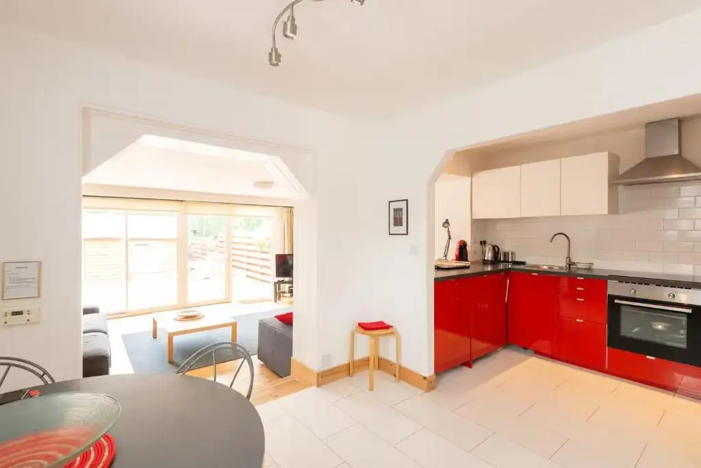 a kitchen with red cabinets and a table at 4guests-2br-privategarden-freeparking in Aviemore