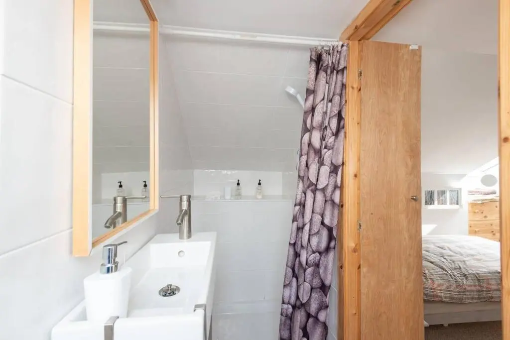 a bathroom with a sink and a mirror and a bed at 4guests-2br-privategarden-freeparking in Aviemore