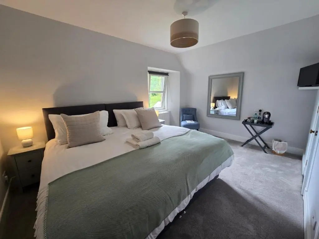 a bedroom with a large bed with two towels on it at Tullochard Guest House in Alness