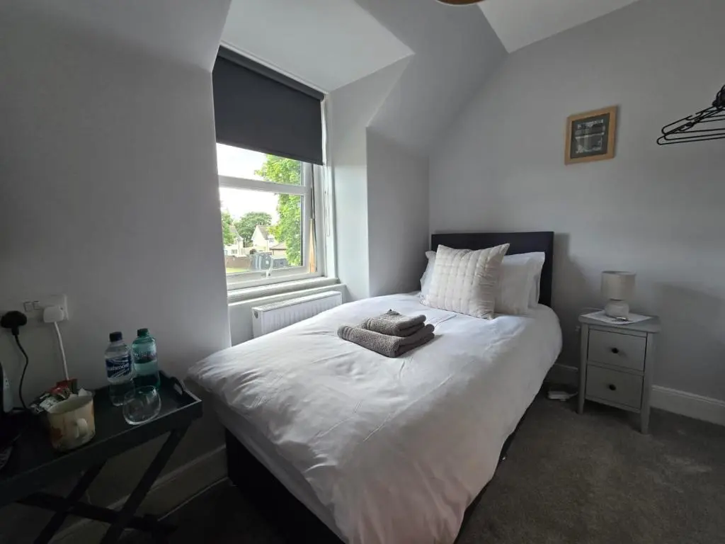 a bedroom with a white bed with a window at Tullochard Guest House in Alness