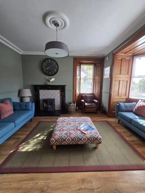 a living room with blue couches and a fireplace at Tullochard Guest House in Alness