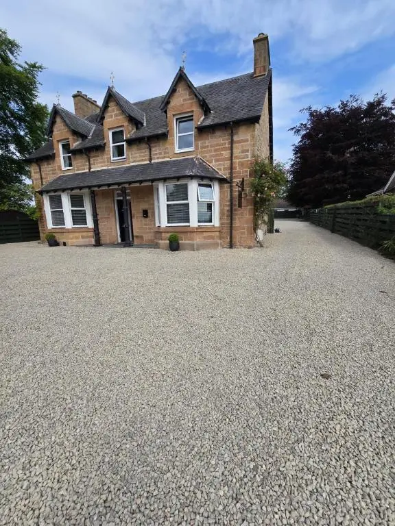 a house with a gravel driveway in front of it at Tullochard Guest House in Alness