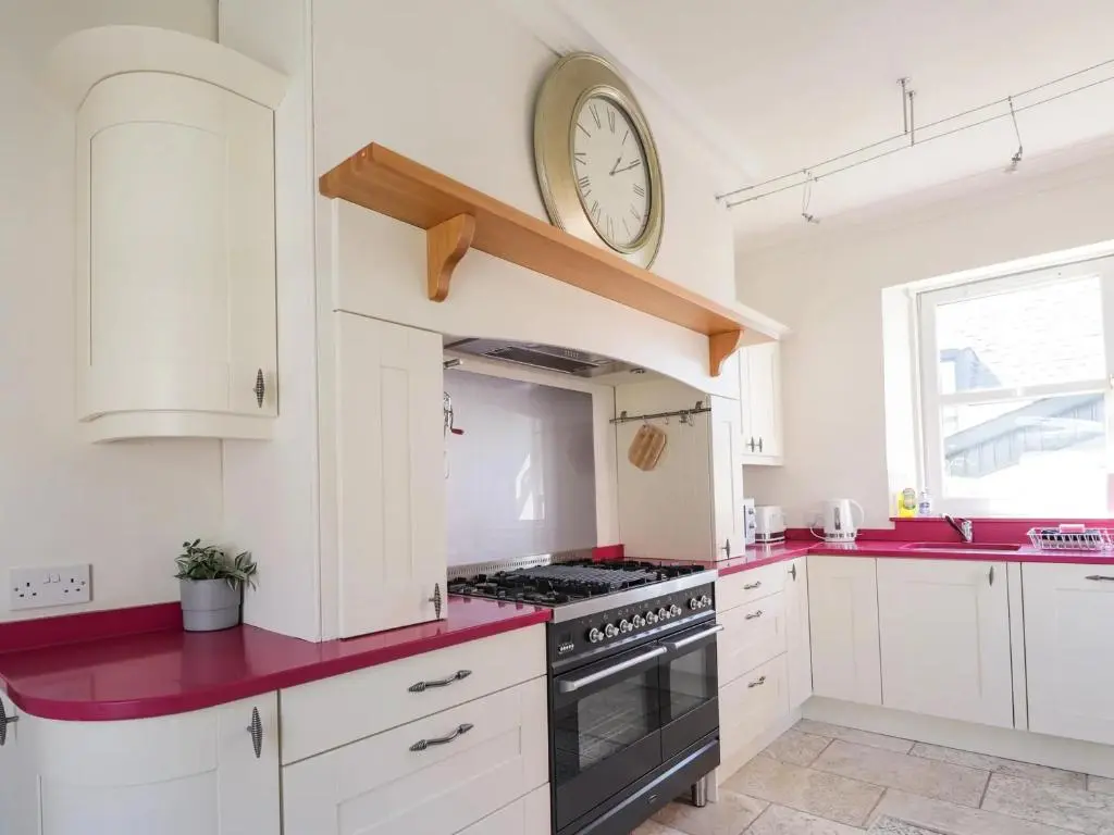 a kitchen with white cabinets and a clock on the wall at Mary Ann Villa in Inverness