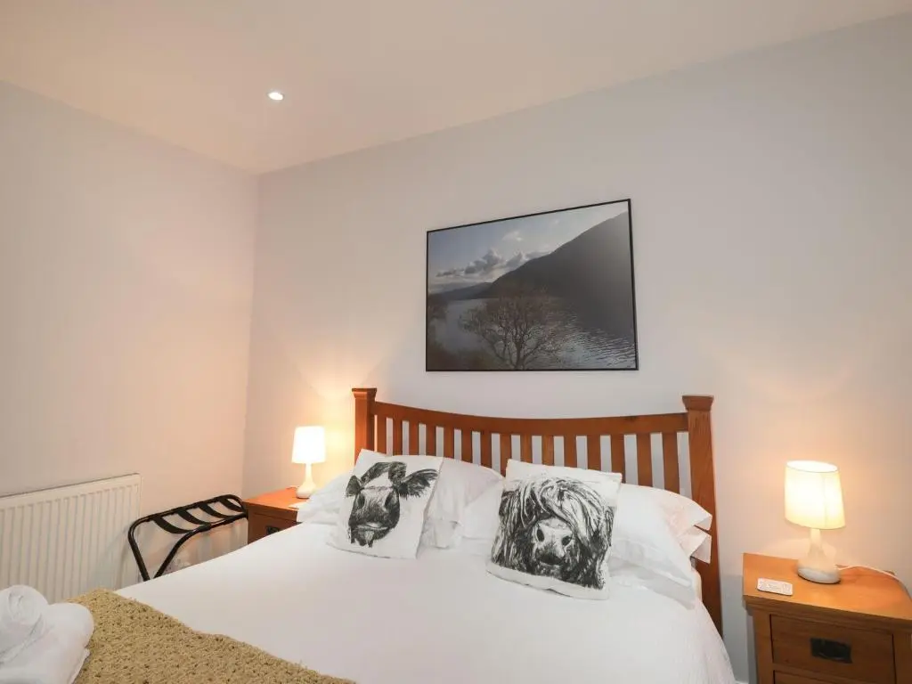 a bedroom with a bed with two pictures on the pillows at Wendy's Place in Inverness