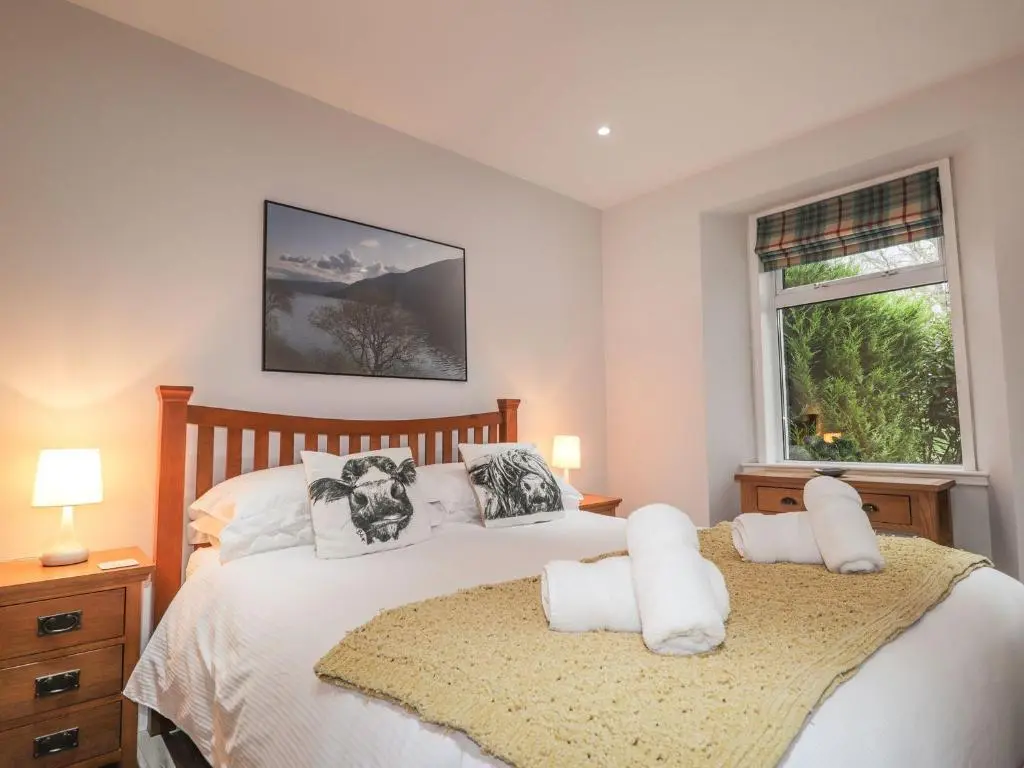 a bedroom with a bed with white sheets and a window at Wendy's Place in Inverness
