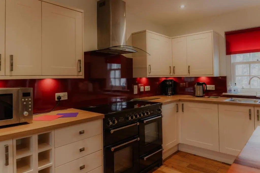 a kitchen with white cabinets and a black stove top oven at Sherrabeg Cottage in Laggan