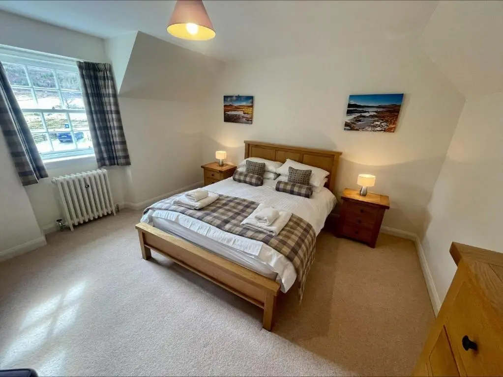 a bedroom with a large bed and two night stands at Sherrabeg Cottage in Laggan
