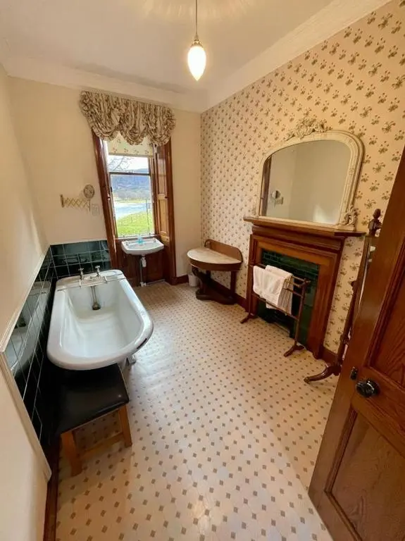 a bathroom with a sink and a mirror and a fireplace at Sherramore Lodge in Laggan