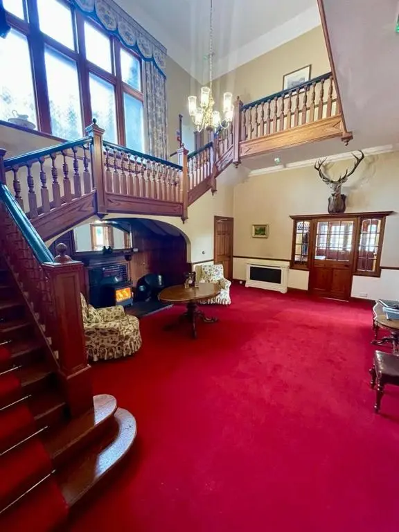 a large room with a staircase and a red carpet at Sherramore Lodge in Laggan