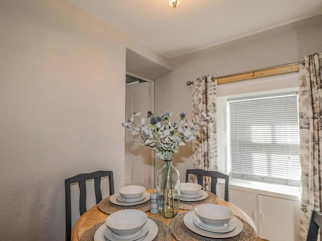 a dining room table with a vase of flowers on it at Porter's Lodge in Inverness