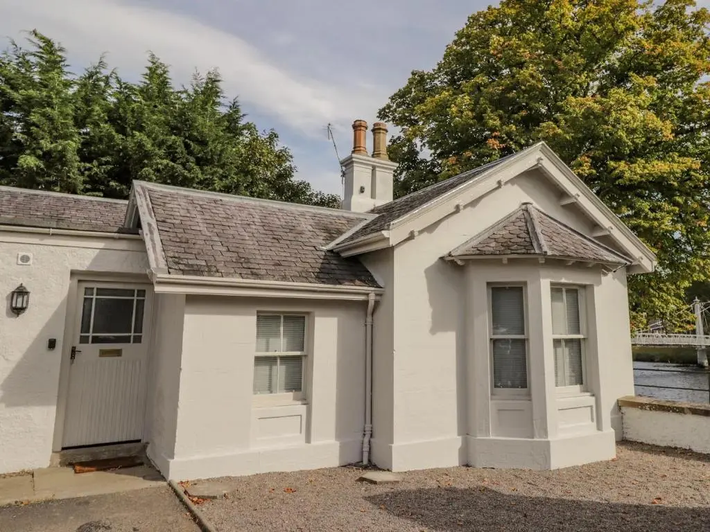 a small white house with a garage at Porter's Lodge in Inverness