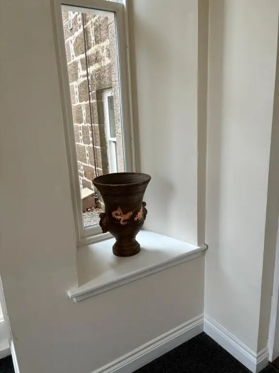 a vase sitting on a shelf next to a window at Junique Modern Ground Floor Apartment - 2 bedrooms in Aberdeen