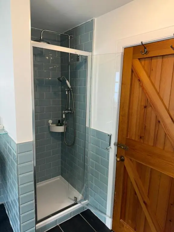a shower with a glass door in a bathroom at Rosebery House with private garden in quiet area of city centre in Inverness