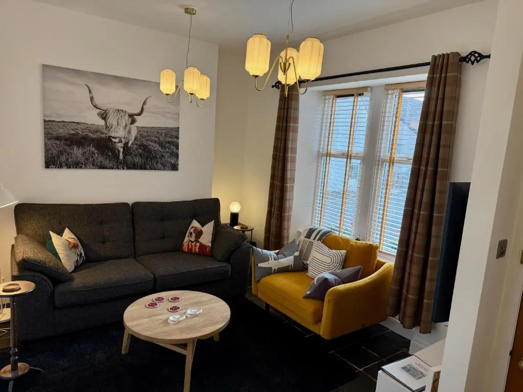 a living room with a couch and a cow on the wall at Rosebery House with private garden in quiet area of city centre in Inverness