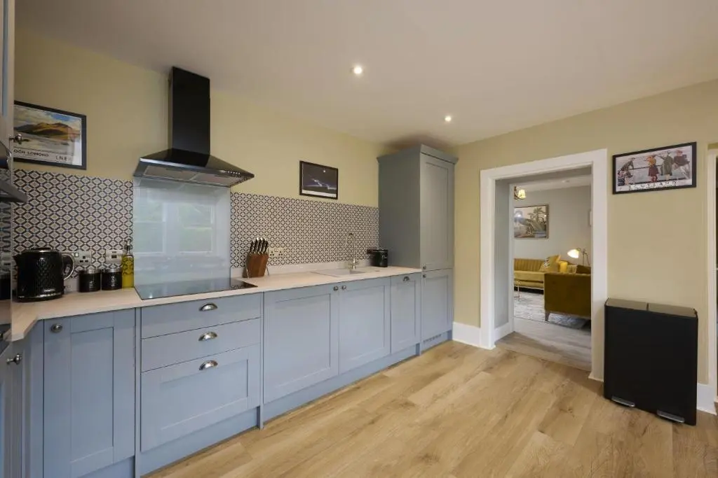 a large kitchen with blue cabinets and a sink at Garden Cottage in Inverness