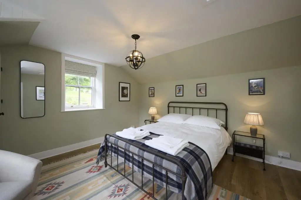 a bedroom with a bed and two lamps and a window at Garden Cottage in Inverness