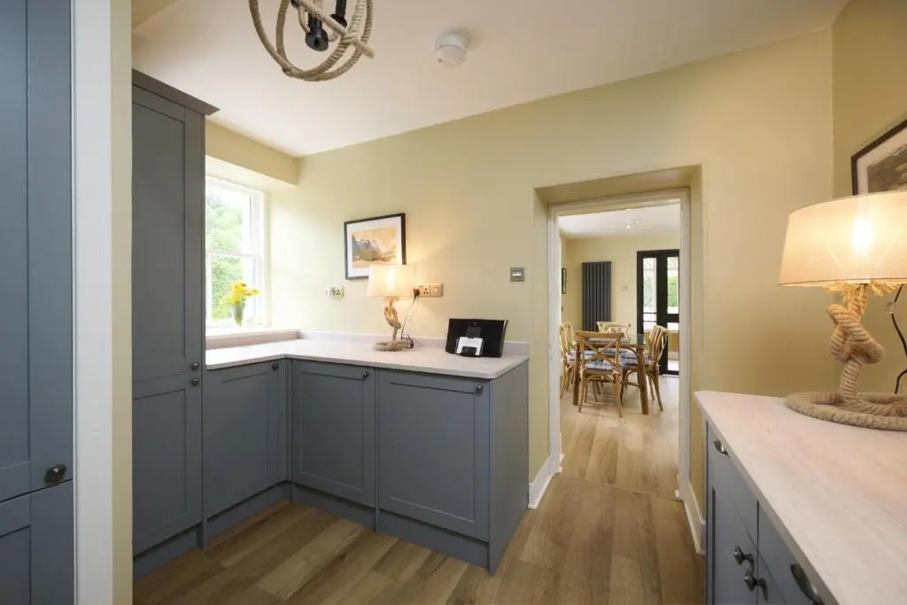 a kitchen with blue cabinets and a dining room at Garden Cottage in Inverness