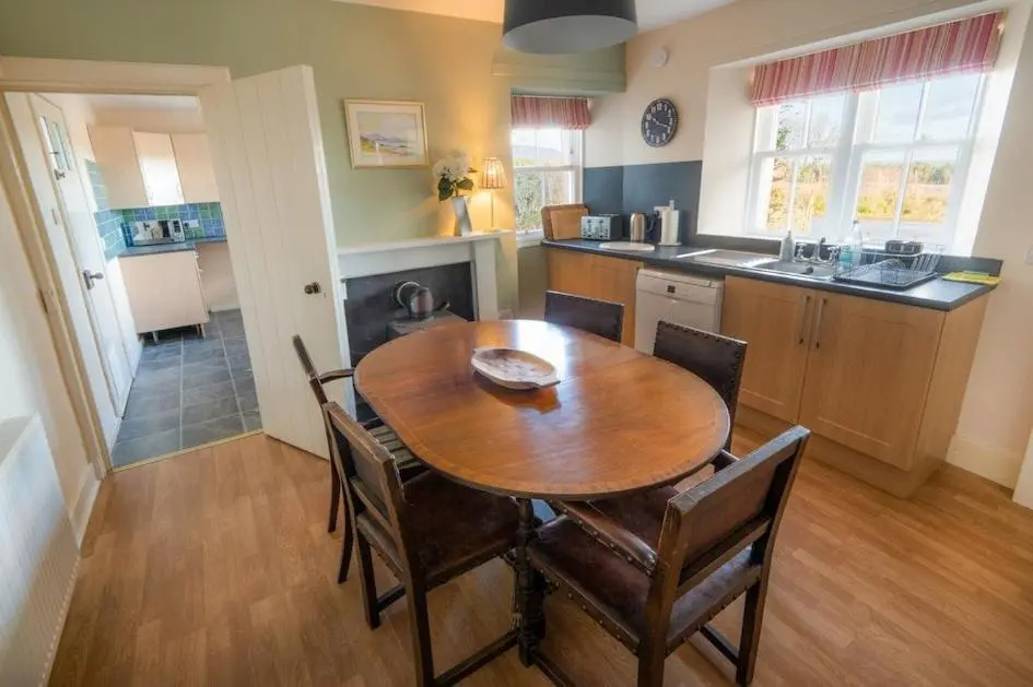 a kitchen with a wooden table and chairs in a room at Foulis Castle Gate Lodge in Evanton