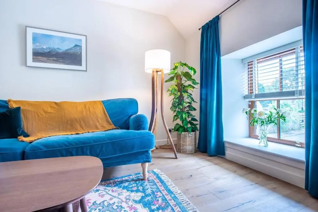 a living room with a blue couch and a table at Weavers Cottage in Inverness