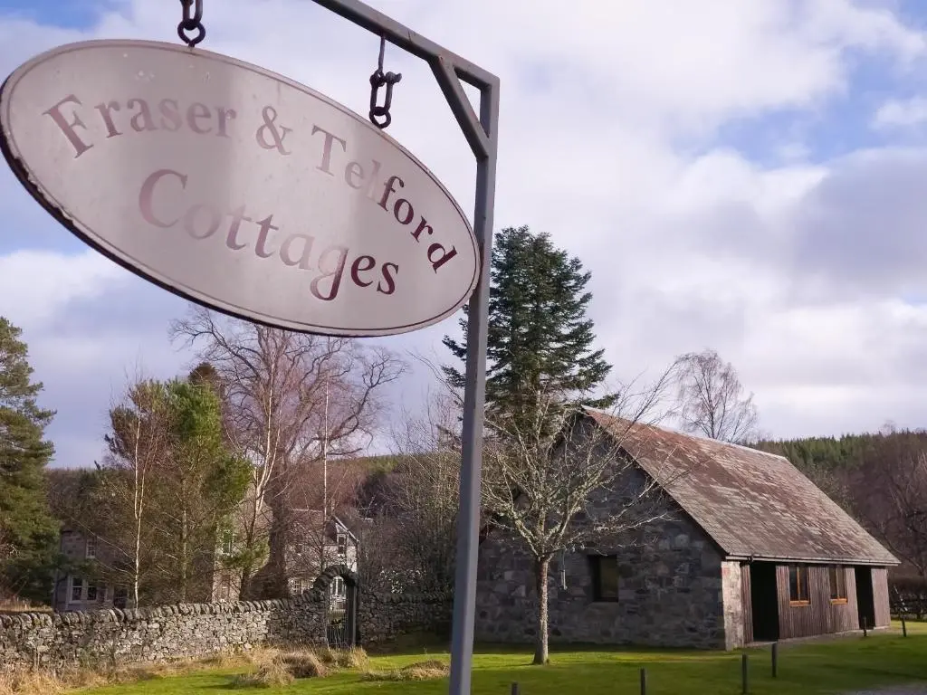 a sign in front of a stone building at Telford Cottage in Kincraig