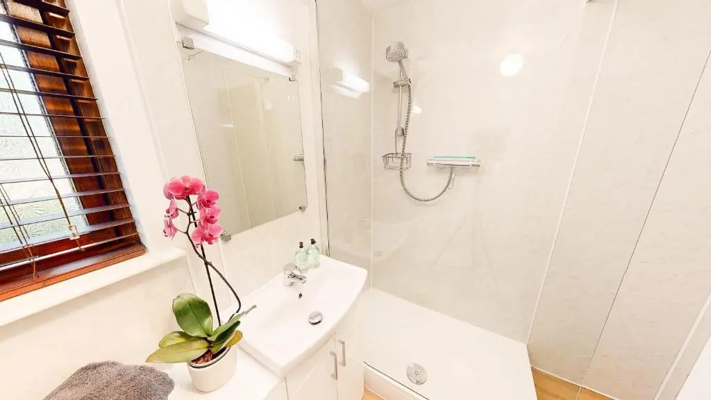 a white bathroom with a sink and a shower at Telford Cottage in Kincraig
