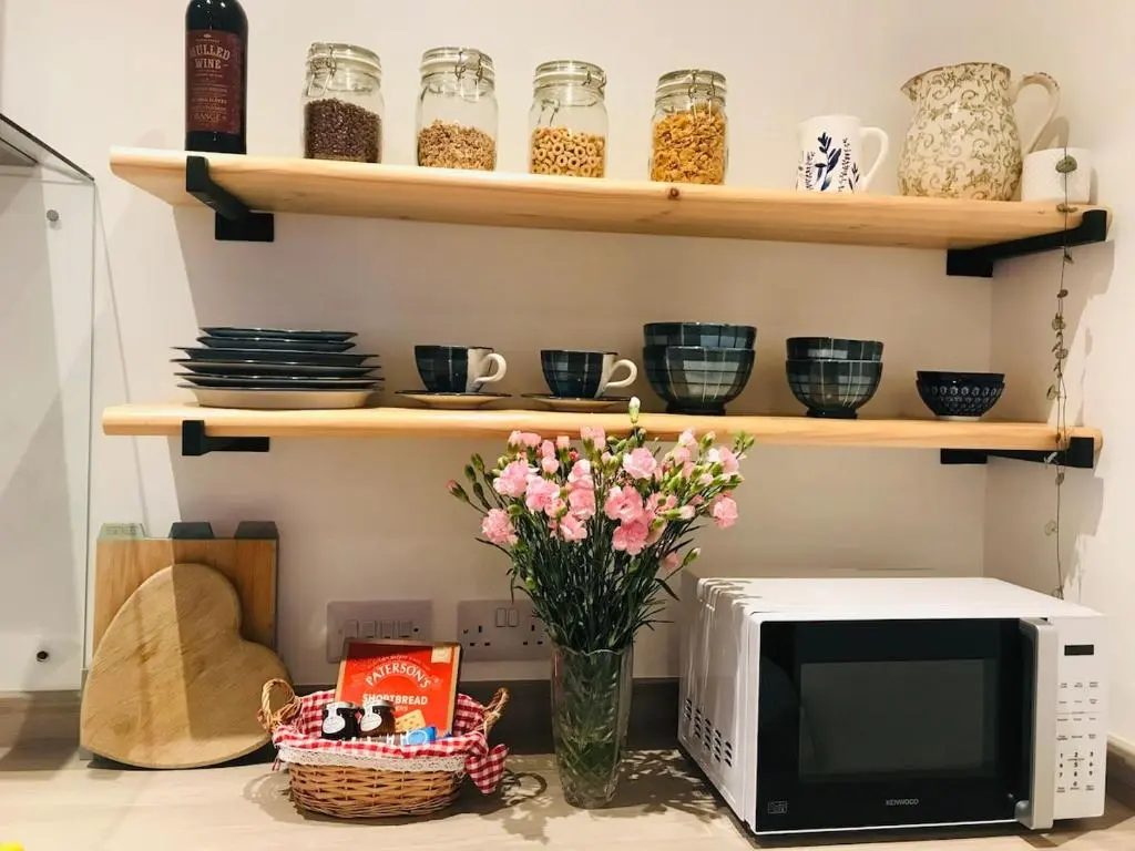 a kitchen counter with a microwave and a vase with flowers at River Retreat - Riverside Apartment in Inverness City Centre in Inverness