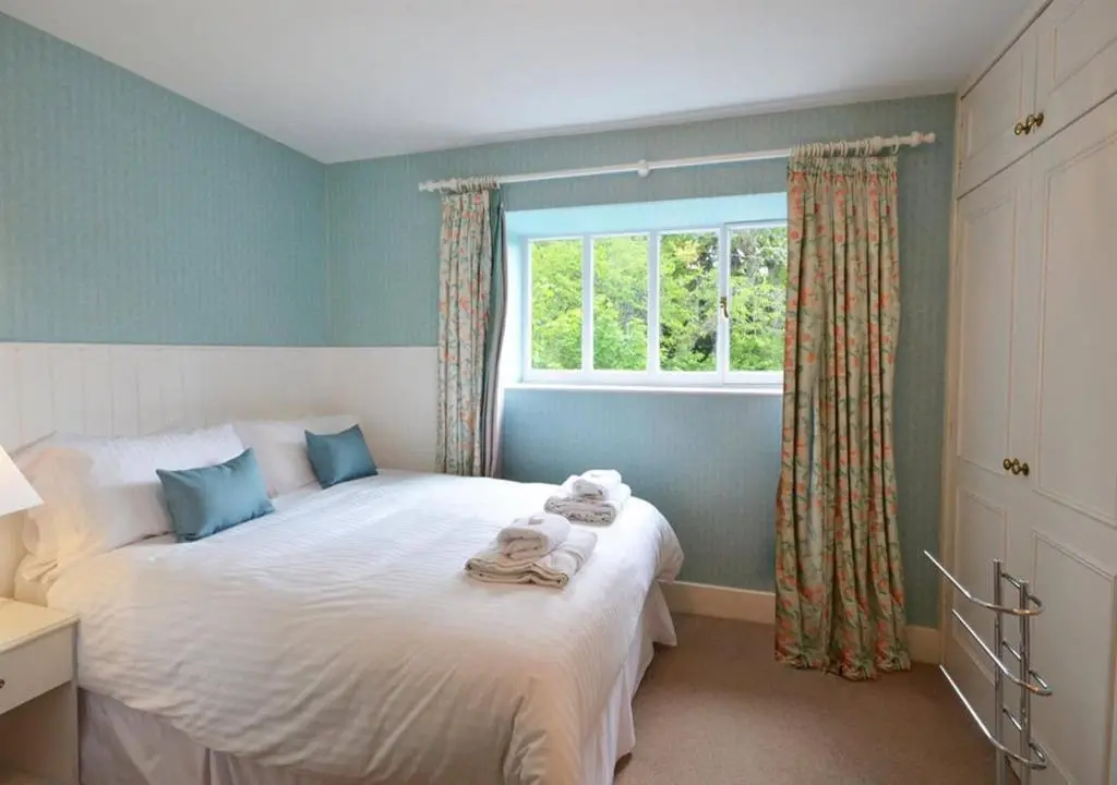 a bedroom with a large white bed with a window at Swiss Cottage in Ballindalloch