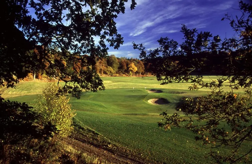 a green golf course with a hole in the grass at Swiss Cottage in Ballindalloch