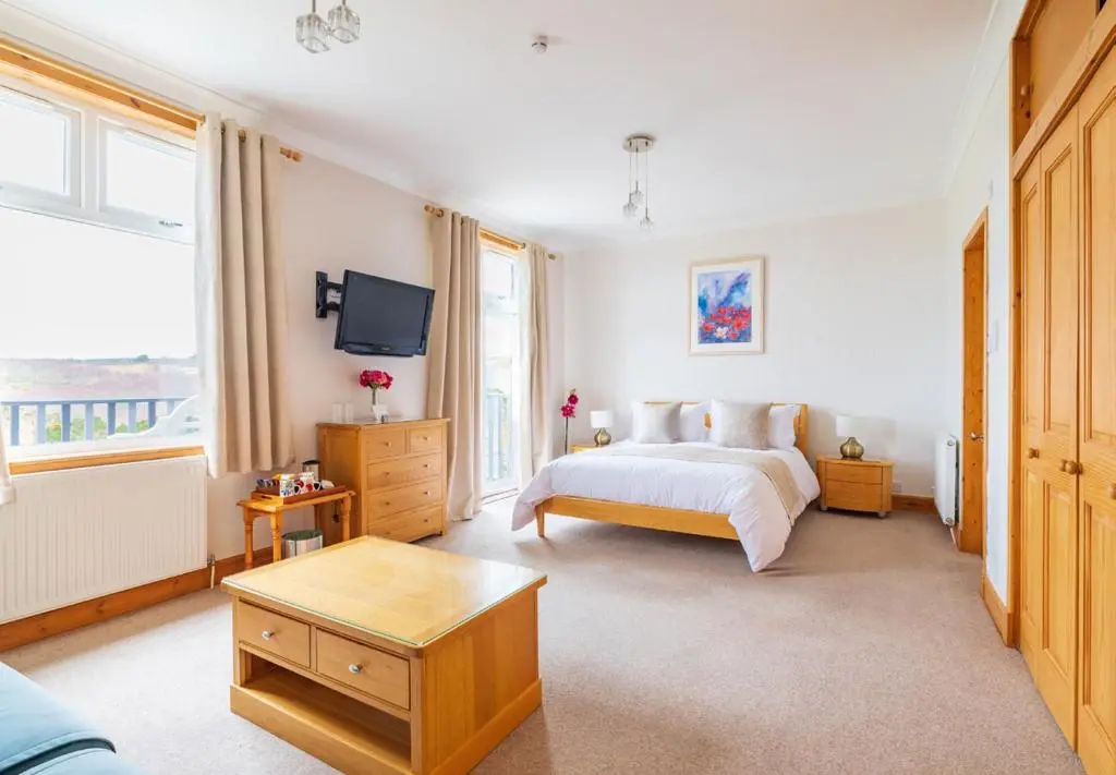 a bedroom with a bed and a tv on the wall at Strathview Lodge B&B in Dornoch