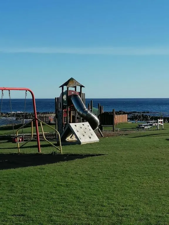 a playground on the beach with the ocean in the background at Hytheview Cottage Whitehills in Whitehills