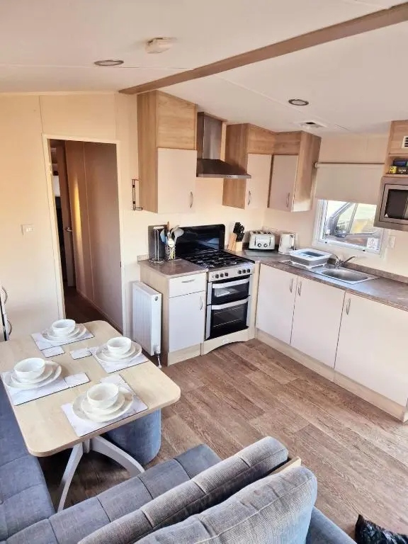 a kitchen and living room with a table and a couch at Badgers Den Silversands in Lossiemouth