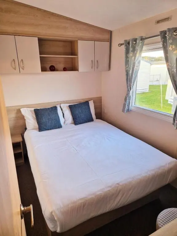 a large bed in a small room with a window at Badgers Den Silversands in Lossiemouth