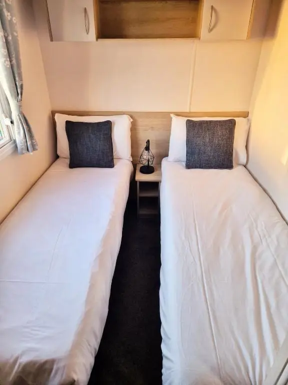 two beds in a small room with a side table at Badgers Den Silversands in Lossiemouth