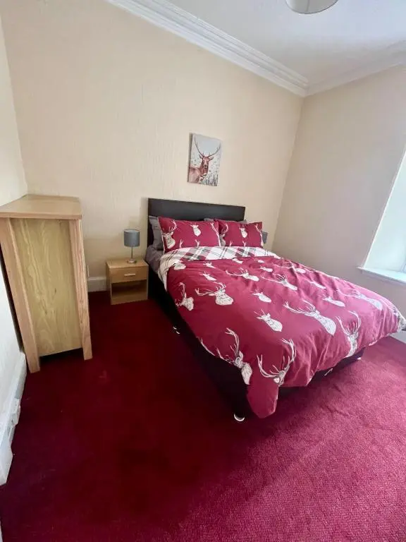a bedroom with a bed with a pink comforter at The Farmhouse Snug in Spean Bridge