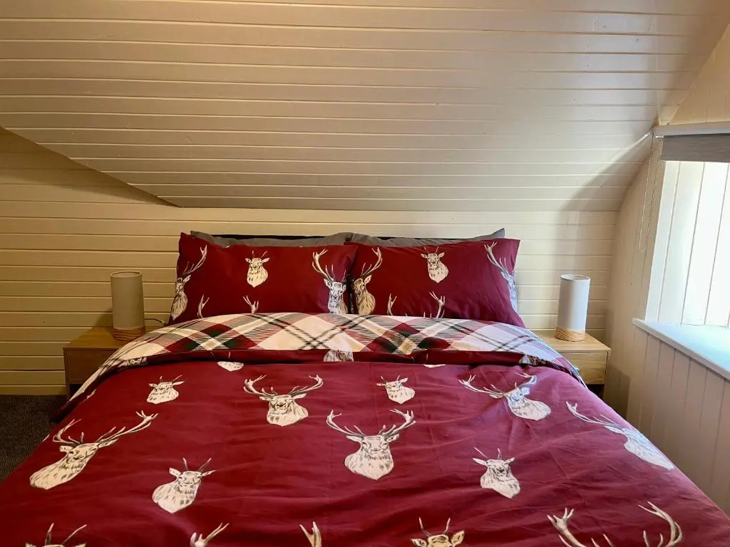 a bed with a bedspread with bugs on it at The Farmhouse Snug in Spean Bridge