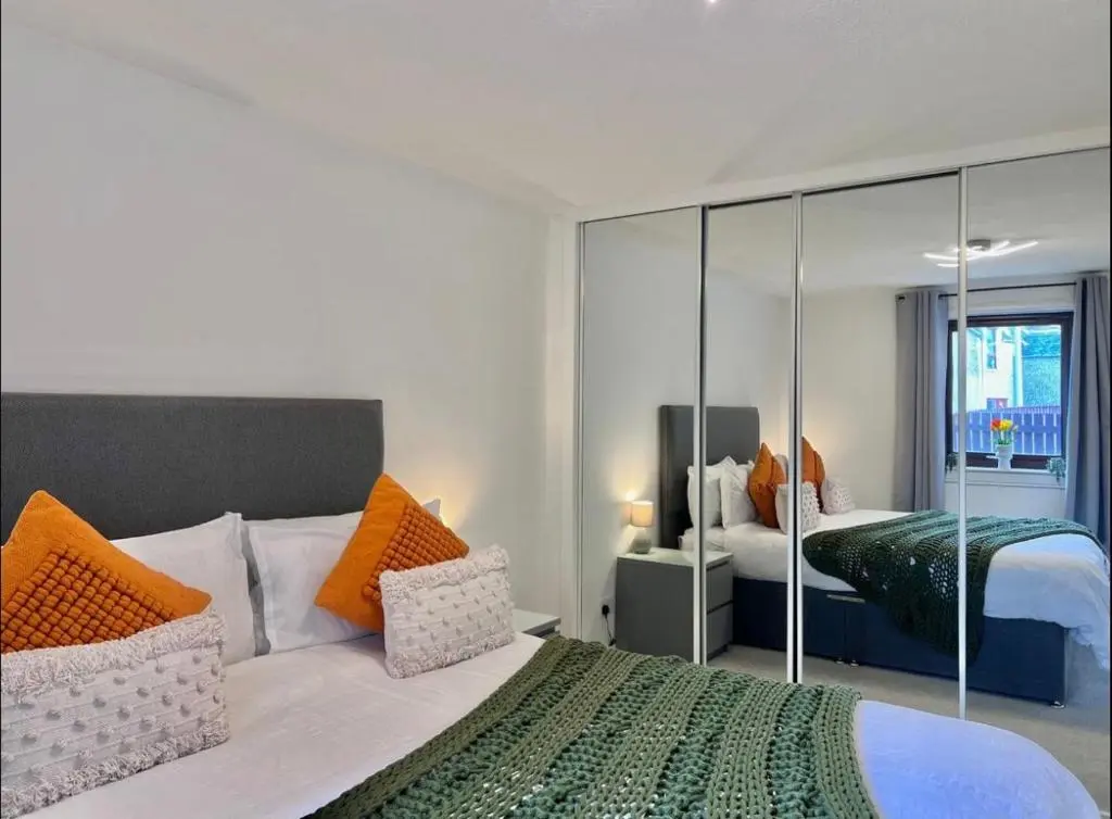 a bedroom with a large bed with orange and white pillows at Charming City Centre Flat in Inverness