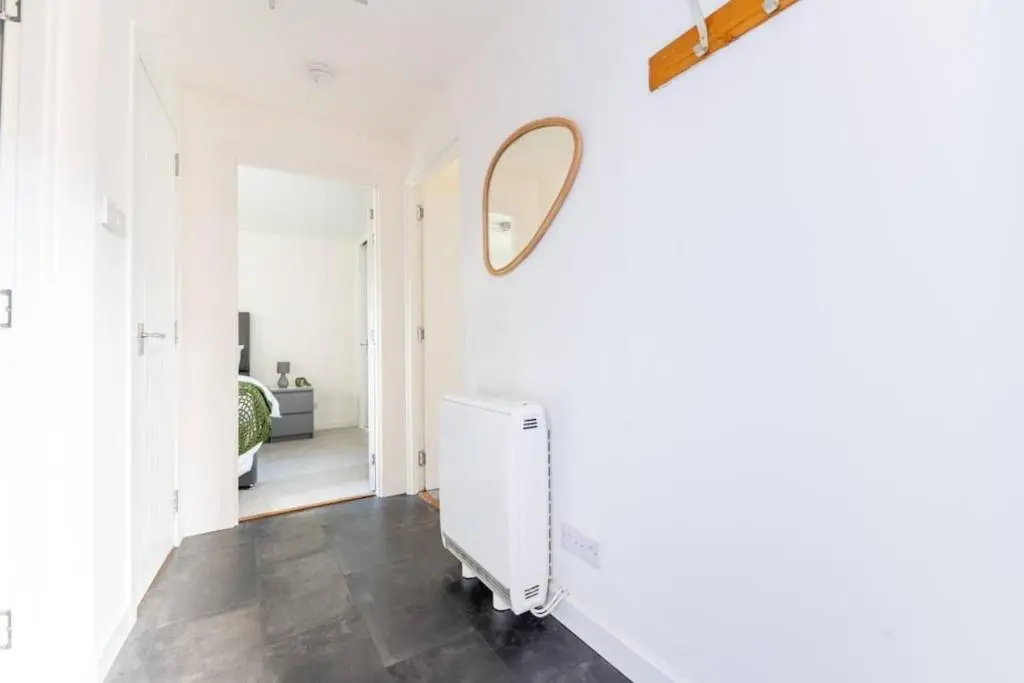 a white hallway with a mirror and a radiator at Charming City Centre Flat in Inverness