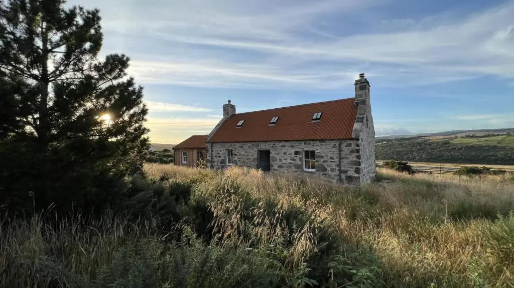 an old stone building in a field with a tree at 2 Bed in Ardgay oc-w30780 in Achnahanat