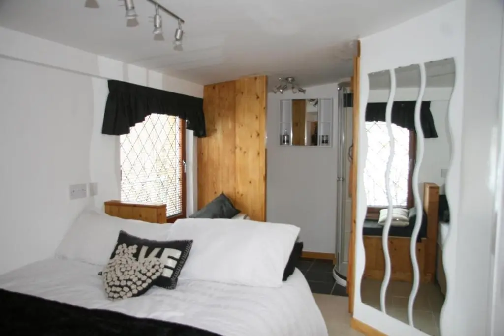 a bedroom with a bed and two windows at Den of Allachlade in Aboyne