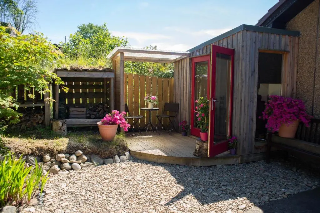 a small wooden house with a table and flowers at Den of Allachlade in Aboyne