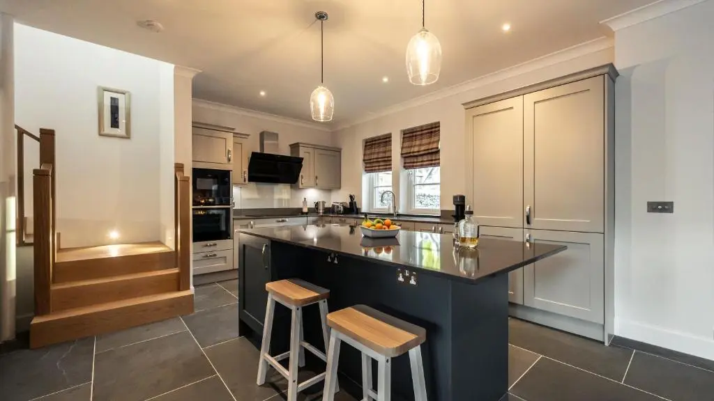 a kitchen with a large island with two bar stools at Holly Tree Cottage in Dornoch