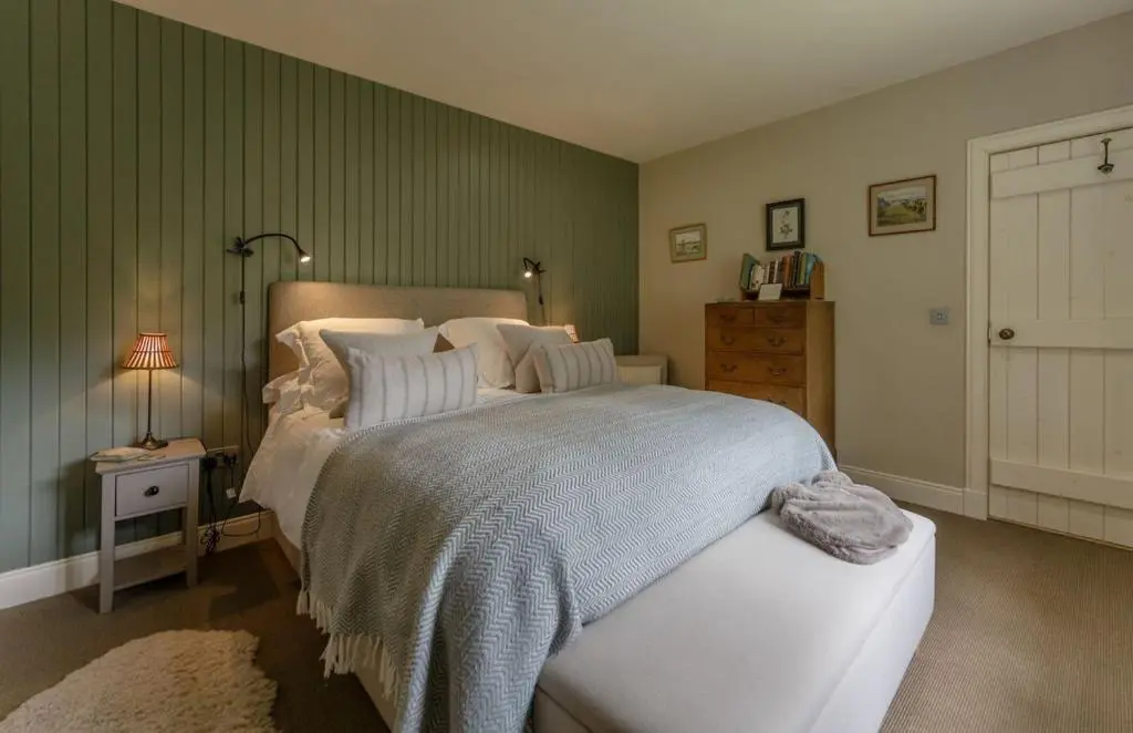 a bedroom with a bed and a lamp and a door at Brachkashie Cottage, Loch Knockie in Whitebridge