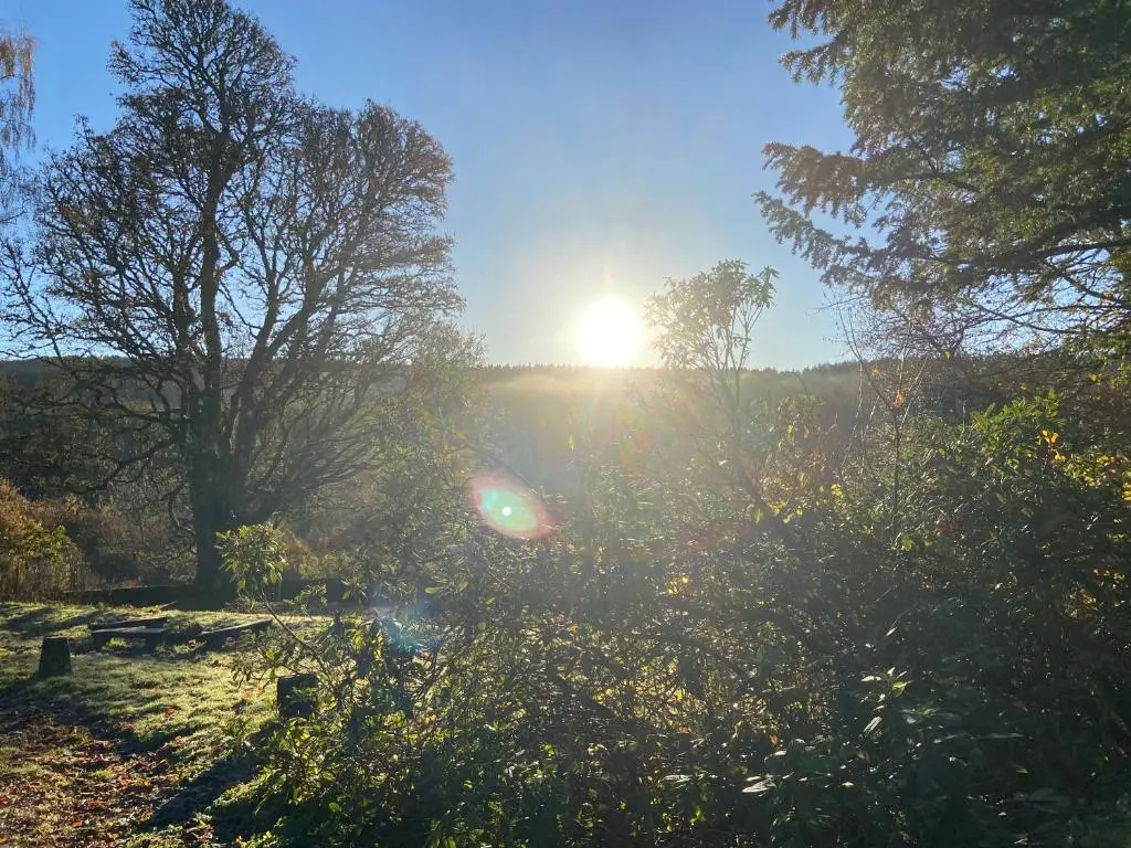 a sun setting over a field with trees and grass at Kirkton Cottage whole house in Cairnie Aberdeenshire in Rothiemay Station