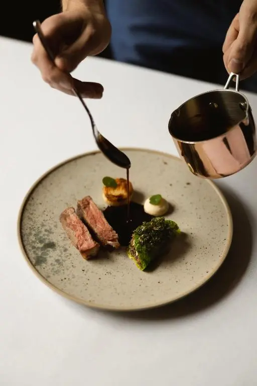 a plate of food with meat and broccoli on a table at The Station Hotel in Rothes